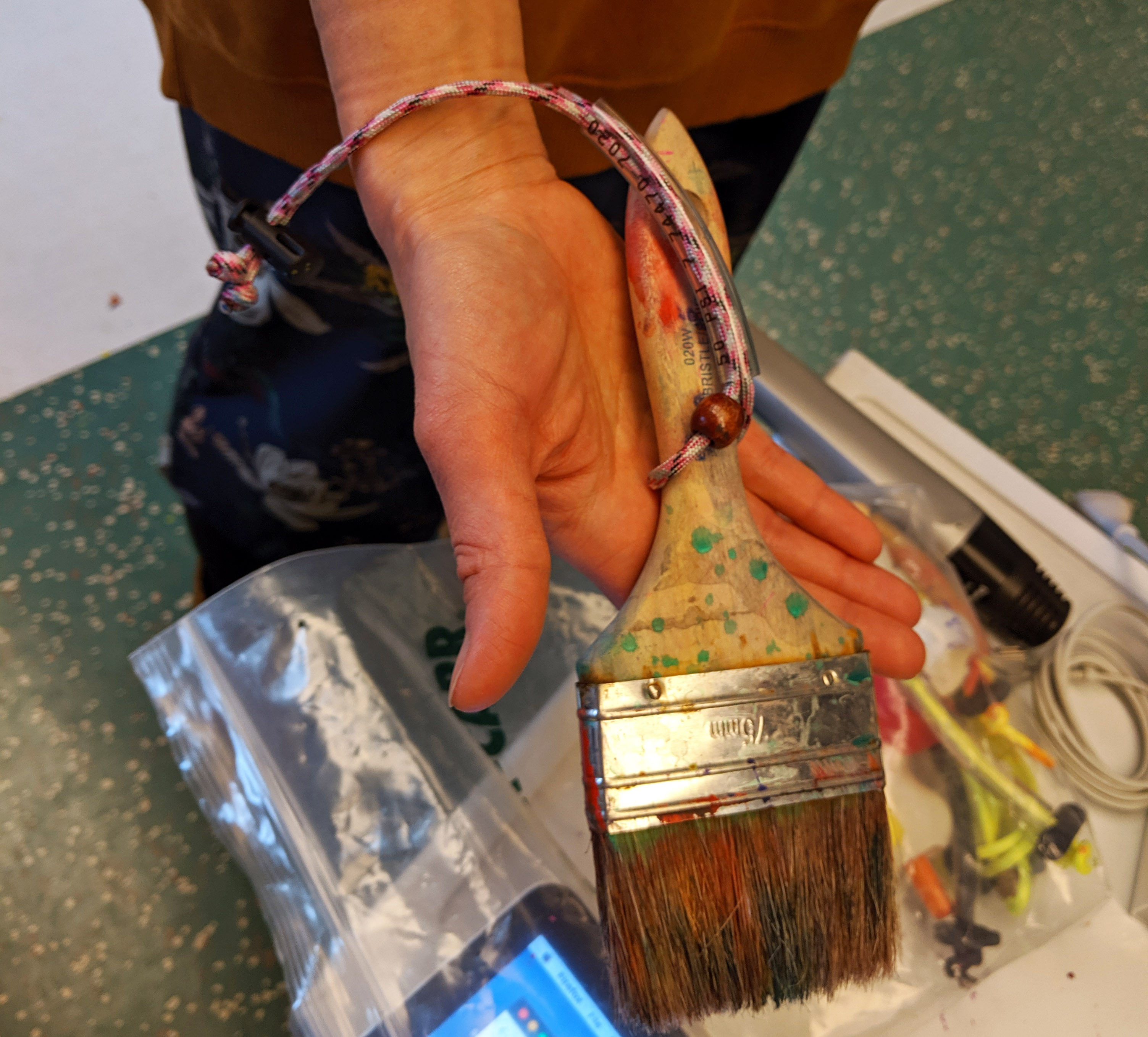 Using a tie to wrap a brush around the student's wrist for further support. Using a tie to wrap a brush around the student's wrist for further support